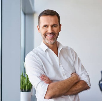 Portrait of smiling mid adult businessman standing at corporate office